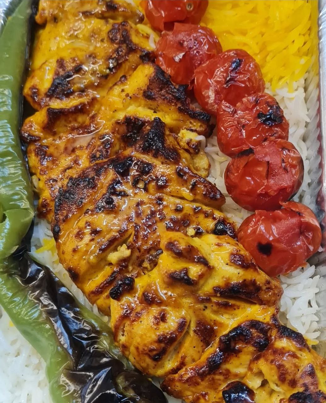 Frisch gegrilltes Safranhähnchen mit Reis und Tomaten